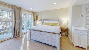 Una camera da letto con un letto, comodini, un armadio e una porta-finestra che dà su un balcone.