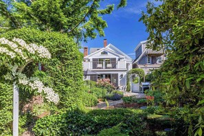 A house with a garden, a covered porch, and a chimney. - Luxury Gallery District home steps from beach with chef’s kitchen & gardens (Provincetown)