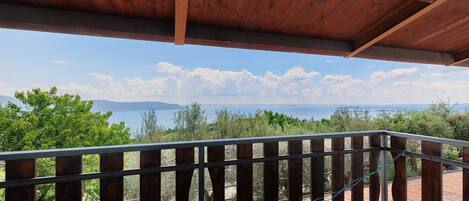Eine Holzterrasse mit Metallgeländer, die auf eine gebirgige Landschaft blickt.
