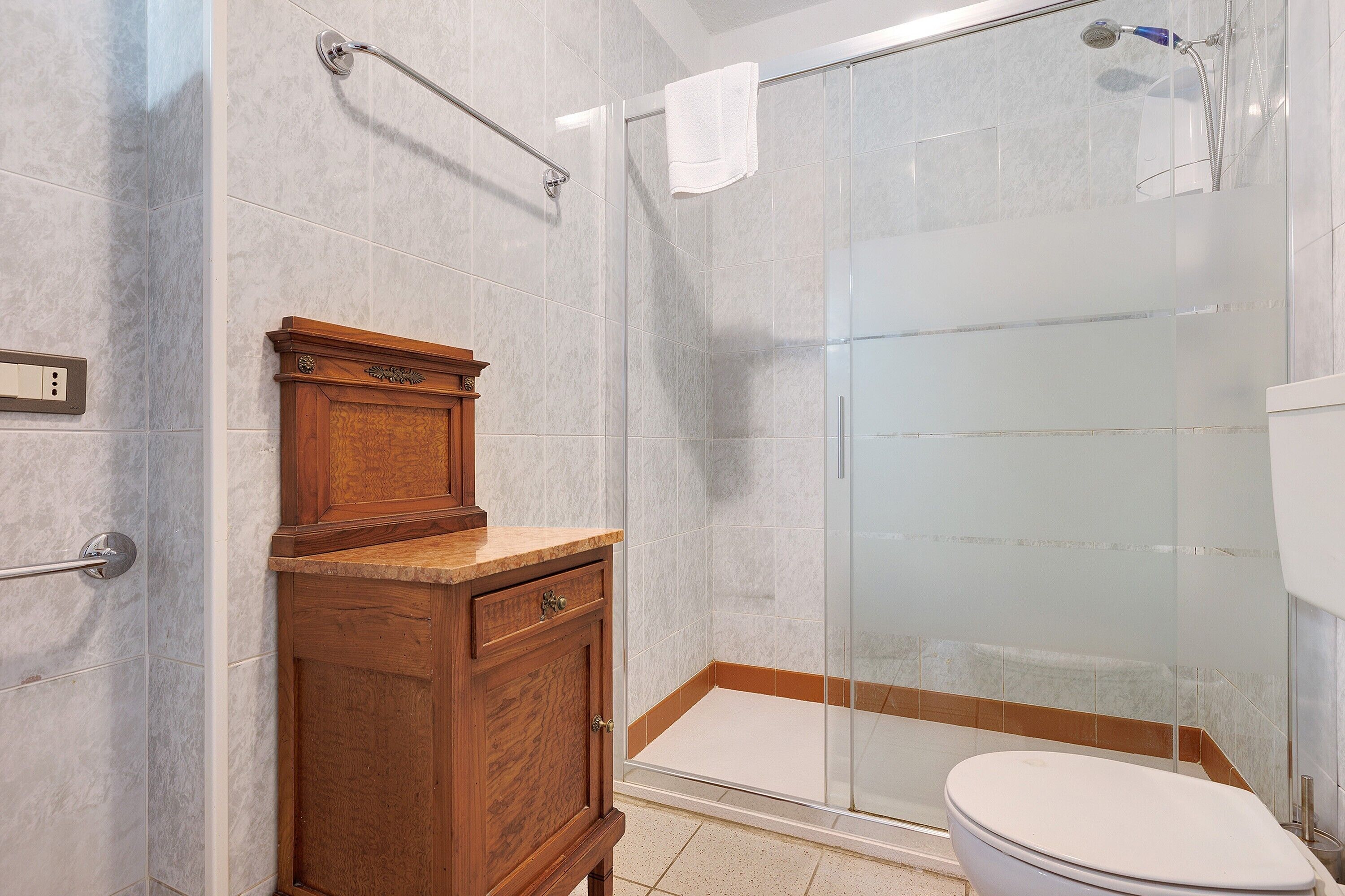 Une salle de bain avec une douche à parois de verre, un meuble-lavabo en bois et des toilettes.