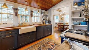 Una cocina con armarios oscuros, encimera de madera, estufa y comedor con mesa y sillas.
