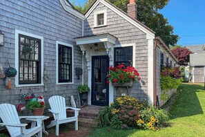 A house with a front porch, two white chairs, and a variety of potted plants. - Stunning West End Home | Historic Restoration | Dog-Friendly (Provincetown)