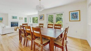 Ein Essbereich mit Holztisch und -stühlen, einer Chandelierleuchtre und Kunstwerken an den Wänden.