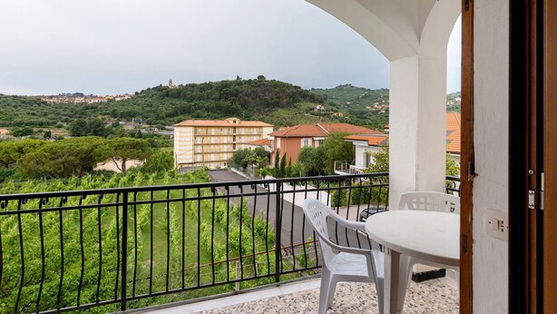 Un balcone con vista su una collina, un tavolo e una sedia.