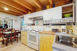 Une cuisine avec des meubles de rangement en bois, une cuisinière, un évier et un coin repas comprenant des chaises et une table.