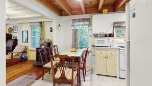 A cozy kitchen with wooden cabinets, a dining table, and chairs. - Cozy island cottage near local attractions with breezy yard & inviting interior (Oak Bluffs)