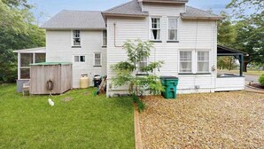 A two-story house with a covered porch, a small shed, and a tree in the yard. - Spacious colonial home close to town with AC, porches, & W/D (Oak Bluffs)