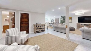 A spacious living room with a sofa set, a television, and a wooden cabinet. - Enchanting home with tennis, firepit, golf nearby & washer/dryer (Oak Bluffs)