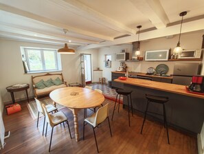 A modern kitchen with a wooden dining table, bar stools, and a built-in island. - Le Clos Morlaisien (Morlaix)