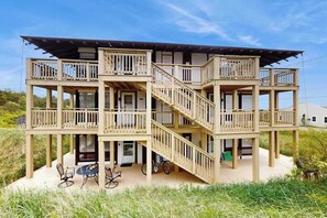 A multi-story wooden building with balconies, a staircase, and outdoor seating. - Cozy studio condo with bay views, deck, and beach steps away (North Truro)
