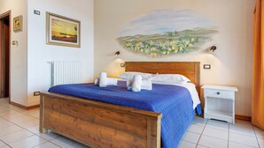 Une chambre à coucher avec un lit en bois, une table de chevet, une lampe fixée au mur et un tableau représentant un paysage.