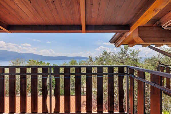 A wooden balcony with a view of mountains and a lake. - Apartment 'Camera Familiare Classic' with Lake View, Shared Garden and Wi-Fi (Toscolano Maderno)