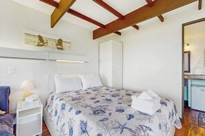 A bedroom with a bed, a nightstand, a chair, a wardrobe, and a mirror.