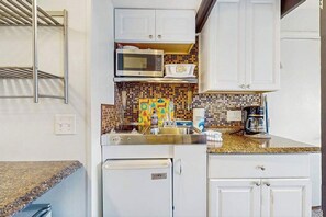 A compact kitchen with a microwave, coffee maker, and a small refrigerator.