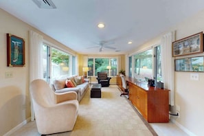 A spacious living room with a sofa, armchairs, a coffee table, a desk, and a ceiling fan. - Private pool close to beach with cabana, grill, AC, patio, dog-friendly (Mashpee)