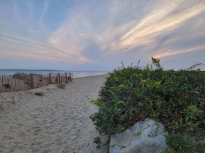 A sandy beach with a wooden fence and dense vegetation. - Private pool close to beach with cabana, grill, AC, patio, dog-friendly (Mashpee)