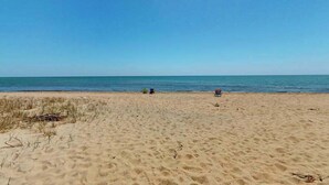 Una playa arenosa con cielo despejado y mar tranquilo.
