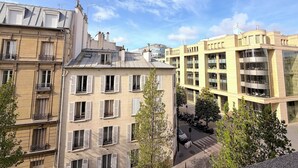 Un immeuble à plusieurs étages doté de balcons, donnant sur la rue, et avec un ciel dégagé.