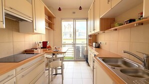 Une cuisine moderne avec un coin repas, des appareils en acier inoxydable et une vue sur l’extérieur grâce à une porte vitrée.