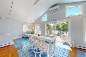 A room with a dining table, chairs, a sofa, and a large window with a view of greenery. - Waterfront property with private dock and access to Nantucket Sound (West Dennis)