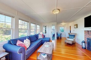 Ein geräumiges Wohnzimmer mit einem blauen Ecksofa, einem Holztisch und einem Kamin.