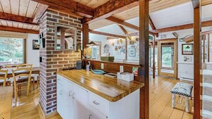 Una cocina con pared de ladrillo, vigas de madera, encimera de madera y un comedor con sillas y mesa.