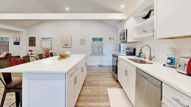 Una cucina moderna con mobili bianchi, un'isola centrale e un'area pranzo con sedie.
