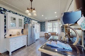 A kitchen with white cabinetry, a central island, and a decorative ceiling light.