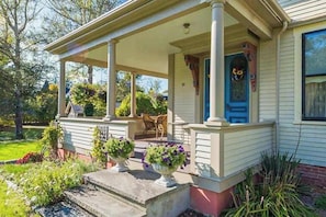 A house with a porch, a blue door, and a garden with potted plants.