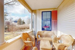 A porch with wicker furniture, a window with shutters, and a view of the outdoors.
