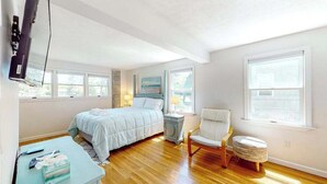 Een slaapkamer met een bed, een stoel, een klein tafeltje en een televisie.