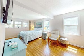Ein Schlafzimmer mit einem Bett, einem Sessel, einem kleinen Tisch und einem Fernseher.