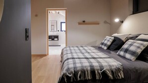 Quarto com cama, mesa de cabeceira, luminária pendente e vista para o banheiro.