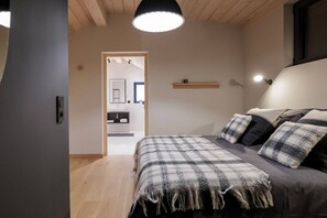 Ein Schlafzimmer mit einem Bett, einem Nachttisch, einer Hängeleuchte und Blick ins Bad.