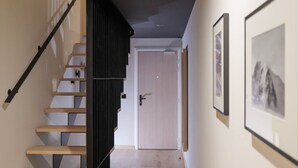 Escada que leva a uma porta, com um quadro na parede à direita.
