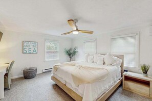 Ein Schlafzimmer mit einem Bett, einem Deckenventilator, einem an der Wand befestigten Schild und einem Fenster mit Jalousien.