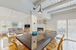 Ein geräumiges Wohnzimmer mit einem großen Holzesstisch, einer Couch und einem Kamin.
