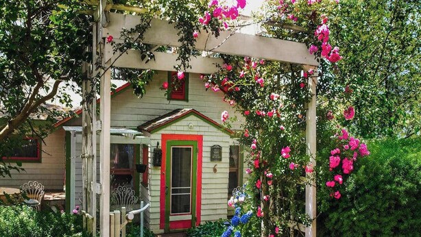 A garden entrance with a wooden archway, a small shed, and lush greenery.