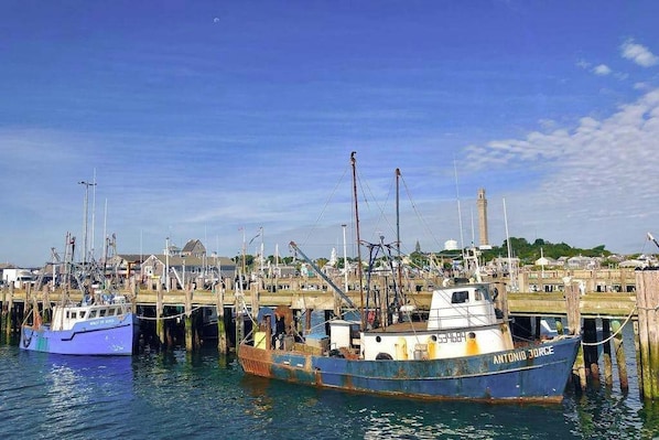 A harbor with boats docked at wooden piers, a clear sky, and a distant building.