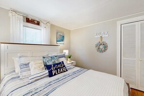 Une chambre à coucher avec un lit, une table de chevet, un élément décoratif mural et une porte.