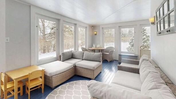Un solárium con un sofá modular, una mesita y una silla de madera.