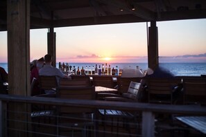 A seaside restaurant with outdoor seating, a view of the ocean, and bottles on the bar counter. - Relaxing fairway escape with resort pools, club access, & steps to Arbor Pool (Brewster)
