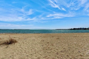 A beach with clear skies and calm water. - Spacious coastal retreat close to beach with modern kitchen, deck, AC, & sunroom (Yarmouth)