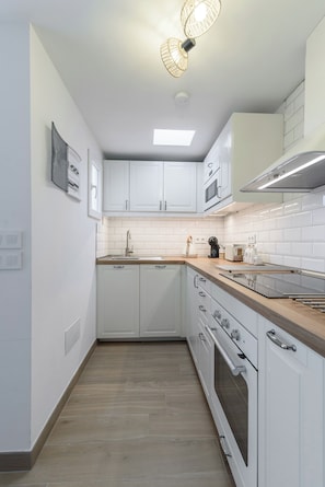 A modern kitchen with white cabinets, a wooden countertop, a built-in oven, and a pendant light. - Home2Book Stylish Duplex Pool & Terrace Maspalomas (Maspalomas)