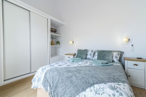 A bedroom with a bed, bedside tables, a wardrobe, and wall-mounted lights. - Home2Book Stylish Duplex Pool & Terrace Maspalomas (Maspalomas)