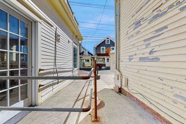 A narrow alleyway between two buildings with a metal railing in the foreground. - Downtown studio w/ full kitchen - walk to Bay and shops! (Provincetown)