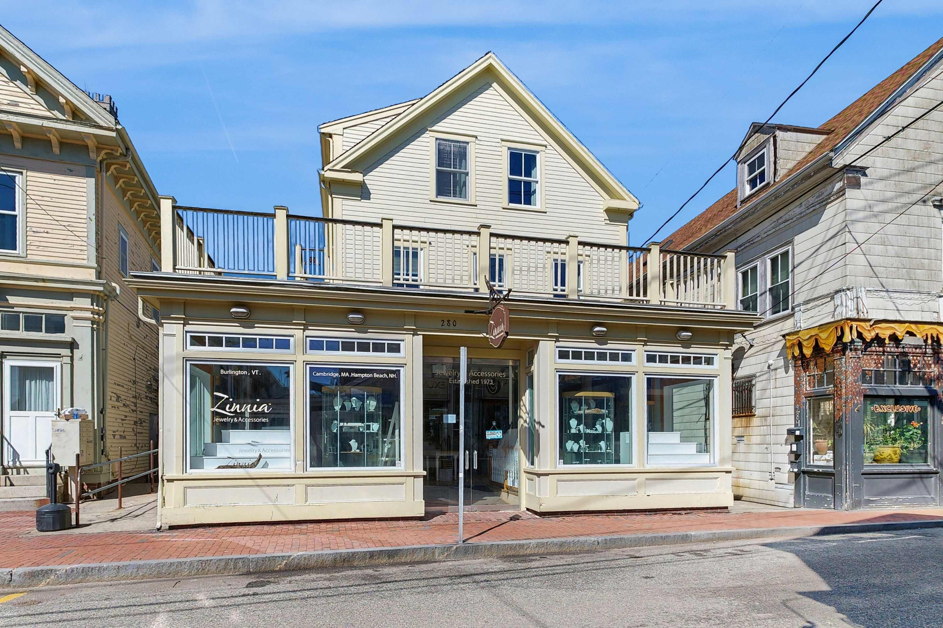 A two-story building with large display windows on the ground floor, a sign for 'Zinnia Jewelry & Accessories,' and a small awning on the right side.