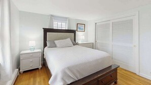 Ein Schlafzimmer mit Bett, Nachttischen, Kommode, Fenster und Kleiderschrank.