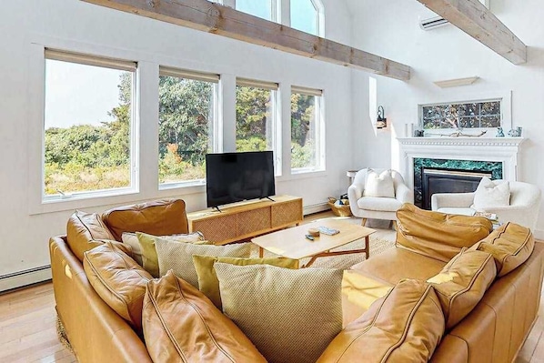 A spacious living room with leather sofas, a flat-screen TV, and a fireplace. - Sun-filled escape with hot tub, deck, bikes, grill, W/D, & Central AC (Truro)