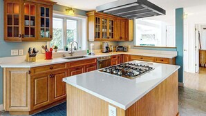 Una cucina moderna con mobili in legno, un'isola centrale e un piano cottura.